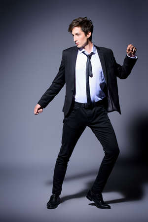 Fashion shot. Handsome young man posing in elegant black suit and white shirt. Studio shot.の写真素材
