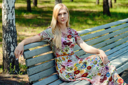 Portrait of a beautiful blonde woman in a summer park.の写真素材