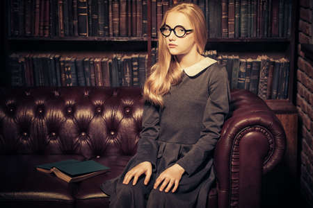 Smart student girl wearing black school dress and glasses is studying at the old library.の写真素材