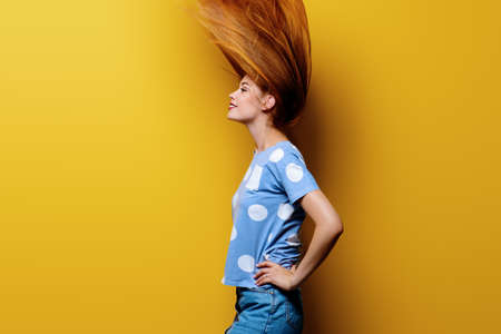 Cute girl with beautiful long flying hair over yellow background. Healthy hair, haircare.の写真素材