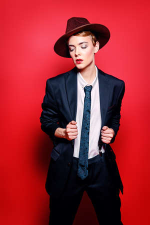 Portrait of an attractive young woman posing in a man's suit and a hat.の写真素材