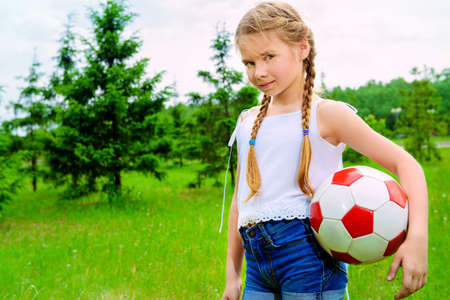 Happy girl plays with a ball in a summer park.の写真素材