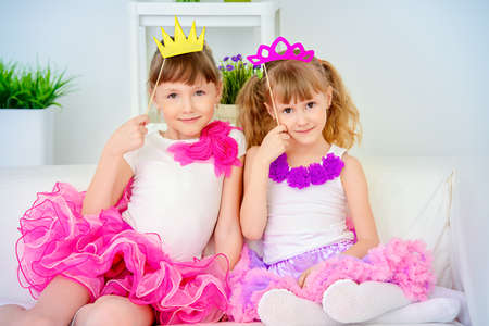 Two little girls sisters playing together with masks. Happy family concept. Carnival, masquerade.の写真素材
