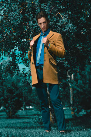 Good-looking young man posing in stylish clothes in a summer park. Outdoor fashion. Business style.の写真素材