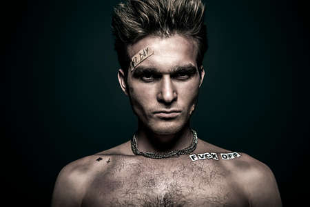Bad boy concept. Close-up portrait of a bad guy showing rudeness and aggression. Rocker, punk.の写真素材