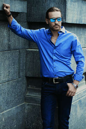 Handsome young man in jeans clothes stands on a city street. Men's fashion.の写真素材