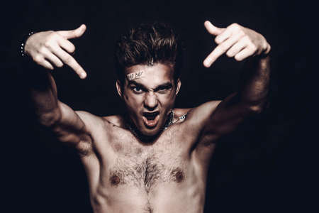 Bad boy concept. A portrait of a bad guy demonstrating antisocial behavior, rudeness and aggression. Rocker, punk.の写真素材