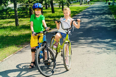 Two happy children riding their bikes. Happy summer holidays.の写真素材