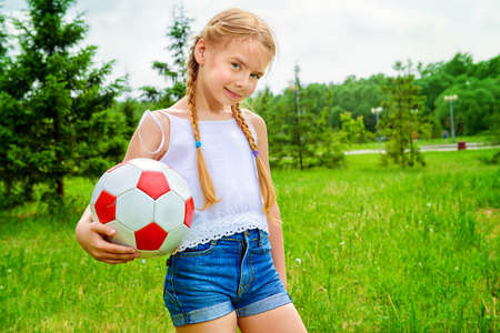 Happy girl plays with a ball in a summer park.の写真素材