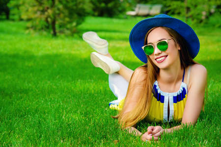 Pretty young woman having a rest on a lawn in a summer park. Beauty, fashion.の写真素材