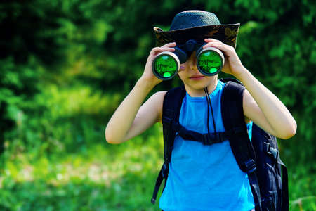 Ten year old boy go hiking with backpack and binocular. Exploring the world. Summer holidays. Outdoor activities.の写真素材