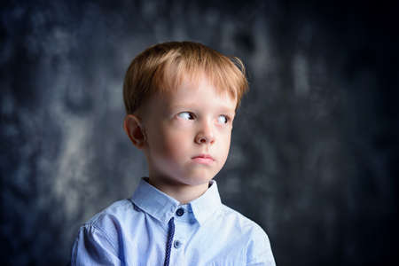 Five year old boy is standing with a puzzled expression. Childhood. Kid's fashion.の写真素材