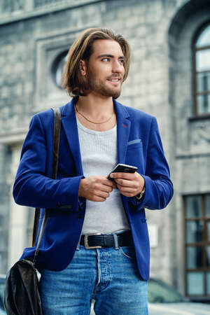 Young businessman walking down the street and using his smartphone. Lively active lifestyle.の写真素材