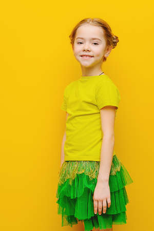 Portrait of a cute happy girl in bright summer clothes over yellow background. Happy childhood. Copy space.の写真素材