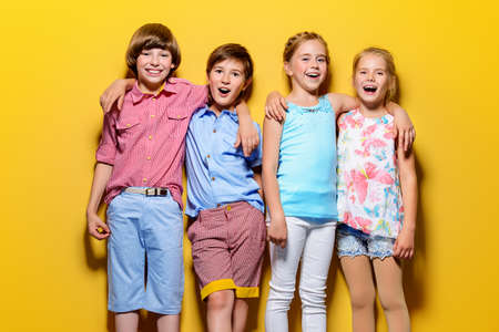 Bright summer children. Group of joyful children posing together over bright yellow background.の写真素材