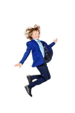 Happy excited boy in school uniform jumping for joy. Isolated over white background. School fashion. Copy space.の写真素材