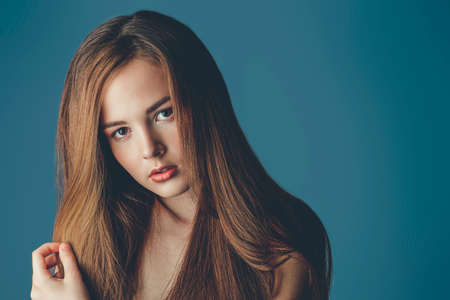 Beauty portrait. Young woman with natural makeup and beautiful long hair over grey background. Cosmetics and makeup. Haircare.の写真素材