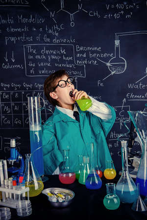 The boy scientist is going to drink the chemical solution he invented. Educational concept. Discovery.の写真素材