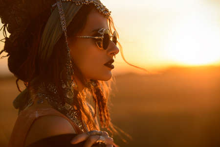 Magnificent fashion woman posing in boho style clothes in the rays of the sunset. Outdoor fashion. Gypsy style.の写真素材