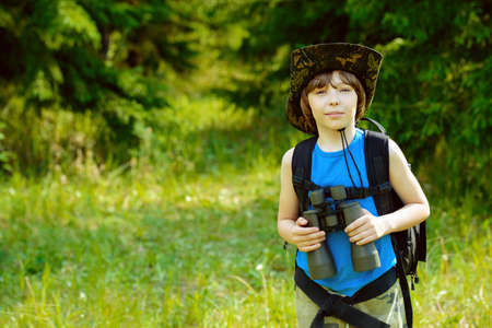 Ten year old boy go hiking with backpack and binocular. Exploring the world. Summer holidays. Outdoor activities.の写真素材