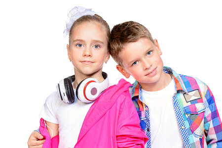 Two cute smiling children, a boy and a girl posing together in bright clothes. Children's fashion. Isolated over white background.の写真素材
