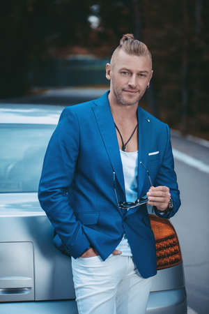 Modern mature man standing by his car. Business style. Vehicle concept. Luxury.の写真素材
