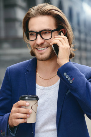 Young businessman walking down the street and talking on his smartphone. Lively active lifestyle.の写真素材