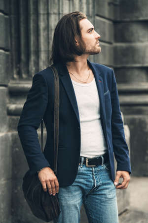 Young businessman walking down the city street. Lively active lifestyle. Male beauty, fashion.の写真素材