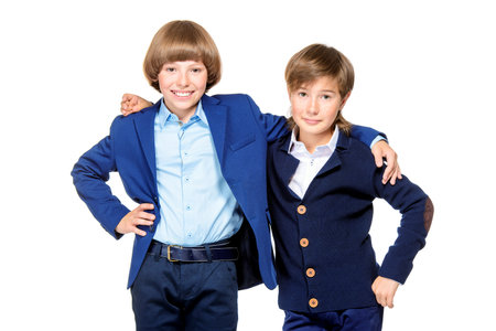 School fashion, uniform. Two handsome schoolboys in elegant suits posing at studio. Isolated over...