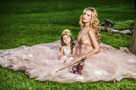 Classical music. Beautiful fairy girl teaches to play the violin a little girl. Musical fairy tales.の写真素材