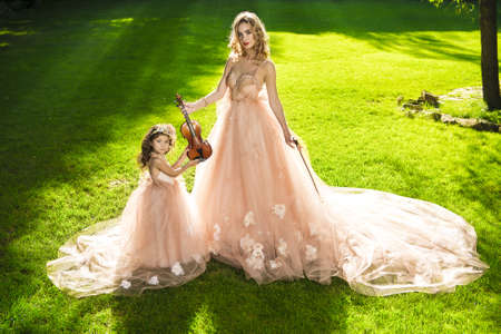 Classical music. Beautiful fairy girl teaches to play the violin a little girl. Musical fairy tales.の写真素材