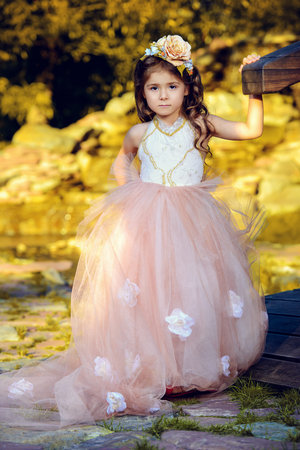 Pretty little girl wearing beautiful dress stands in a summer park. Children's fashion. Birthday.