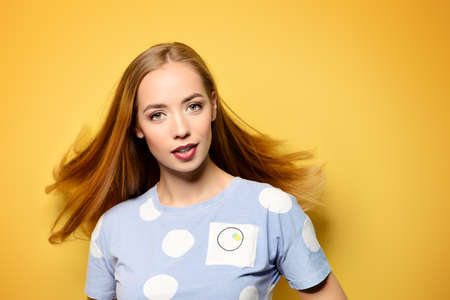 Cute girl with beautiful long flying hair over yellow background. Healthy hair, haircare.の写真素材