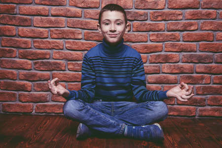 Portrait of a smiling nine year old boy sitting on a floor like yoga.の写真素材