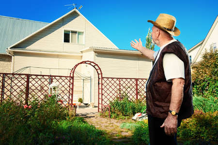 Happy retired senior man,  full of health, standing in his garden near the house. Sunny summer day.の写真素材