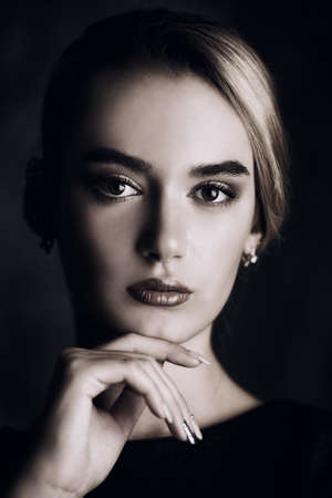 Portrait of a beautiful elegant young woman wearing black dress. Beauty, fashion concept. Make-up and cosmetics. Studio shot.の写真素材