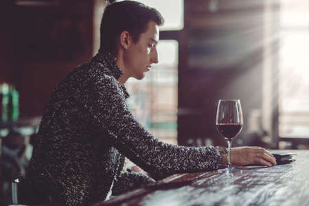 Handsome young man spends time in a wine restaurant.の写真素材
