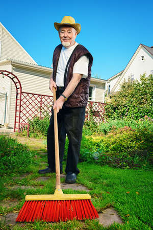 Raking in the garden. Happy senior man gardening in retirement.の写真素材