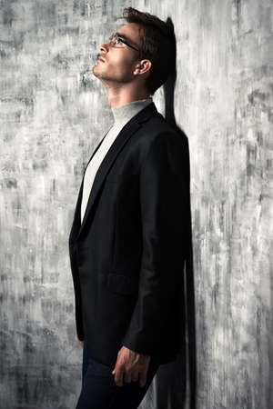 The man in the suit leaned against the wall with his back and thinks. Business concept.の写真素材