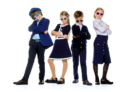 Group of modern children posing in school uniform and sunglasses. School fashion. Isolated over...
