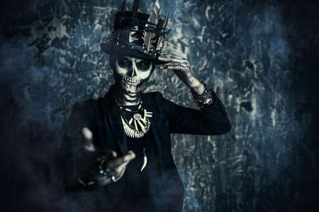 Close-up portrait of a man with a skull makeup dressed in a tail-coat and a top-hat. Baron Saturday. Baron Samedi. Dia de los muertos. Day of The Dead. Halloween.の写真素材