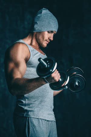 Muscular sportsman bodybuilder doing exercises with dumbbells. Health and sports concept.の写真素材