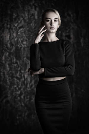 Elegant blonde young woman wearing black fitting dress. Beauty, fashion concept. Studio shot.の写真素材