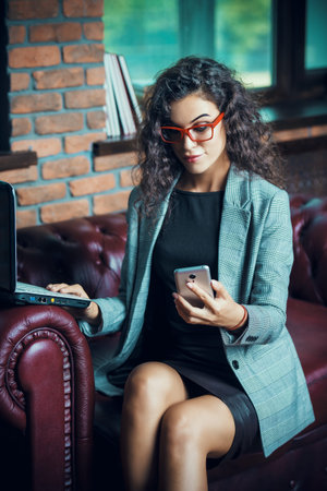 Businesswoman is working with a laptop and cell phone at the office.の写真素材