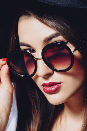 Close-up portrait of a hipster girl wearing hat and round sunglasses. Beauty, cosmetics.の写真素材