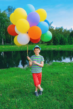 Happy boy enjoys with a sunny summer day and balloons. Summer holidays. Birthday.の写真素材