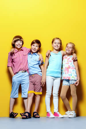 Bright summer children. Group of joyful children posing together over bright yellow background.の写真素材