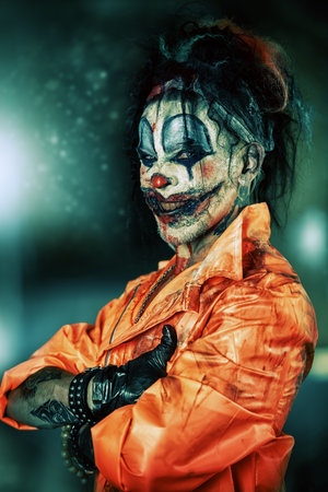 Sinister clown man stained in blood is standing in an abandoned house. Male zombie clown. Halloween....