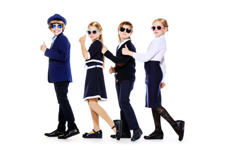 Group of modern children posing in school uniform and sunglasses. School fashion. Isolated over...