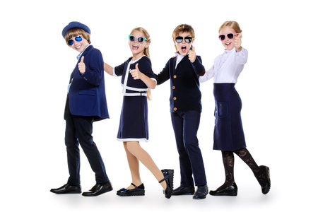 Group of modern children posing in school uniform and sunglasses. School fashion. Isolated over...